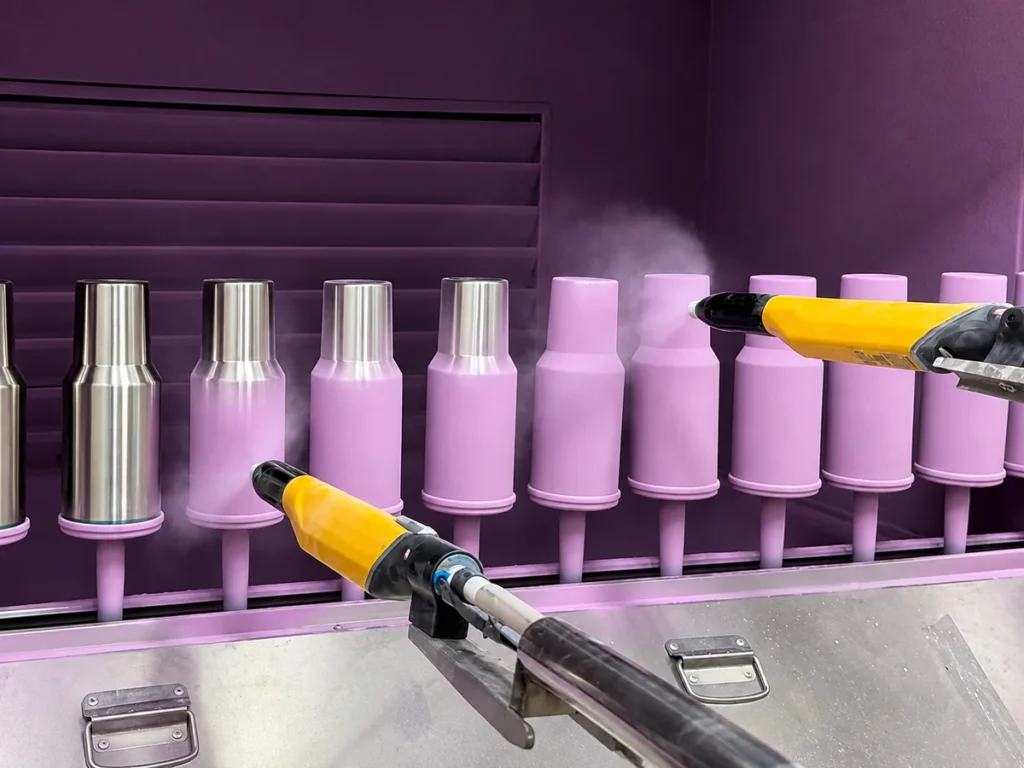 Stainless steel tumblers undergoing custom Pantone color coating in a drinkware factory
